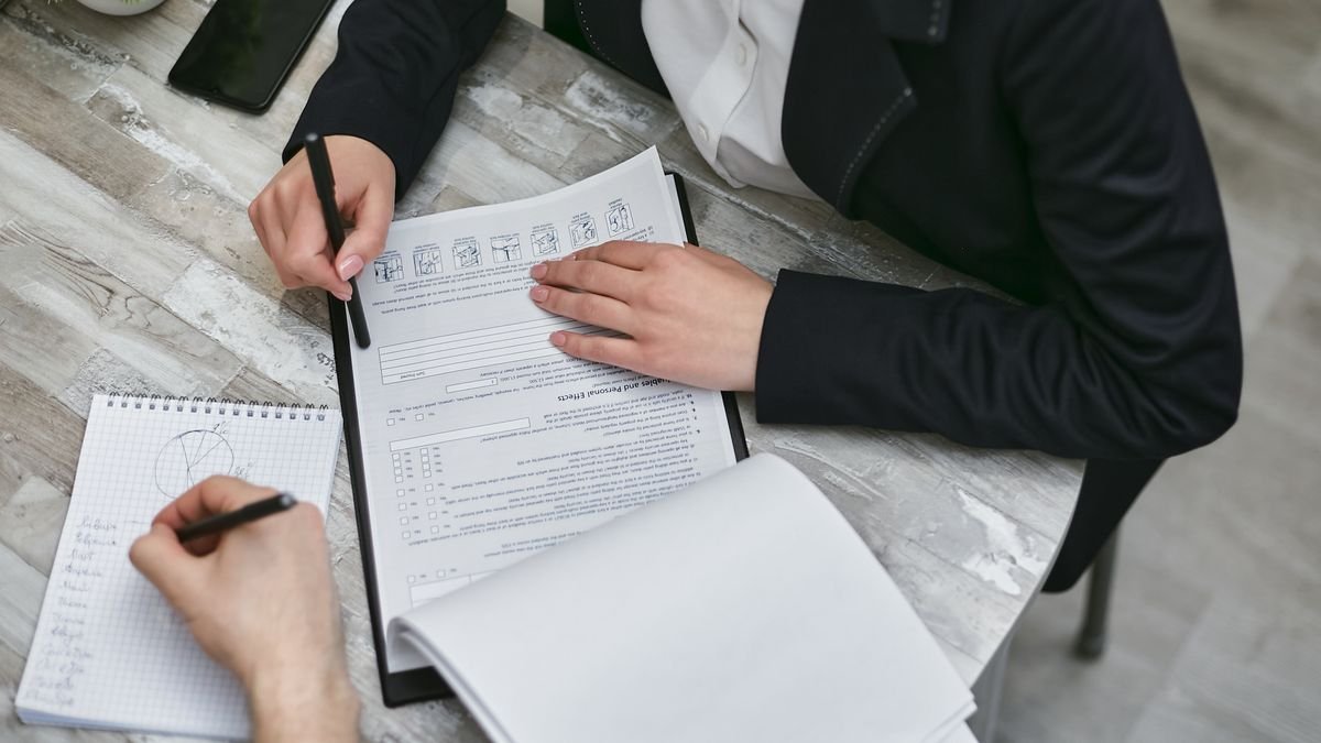 Two colleagues reviewing documents and taking notes at an office desk