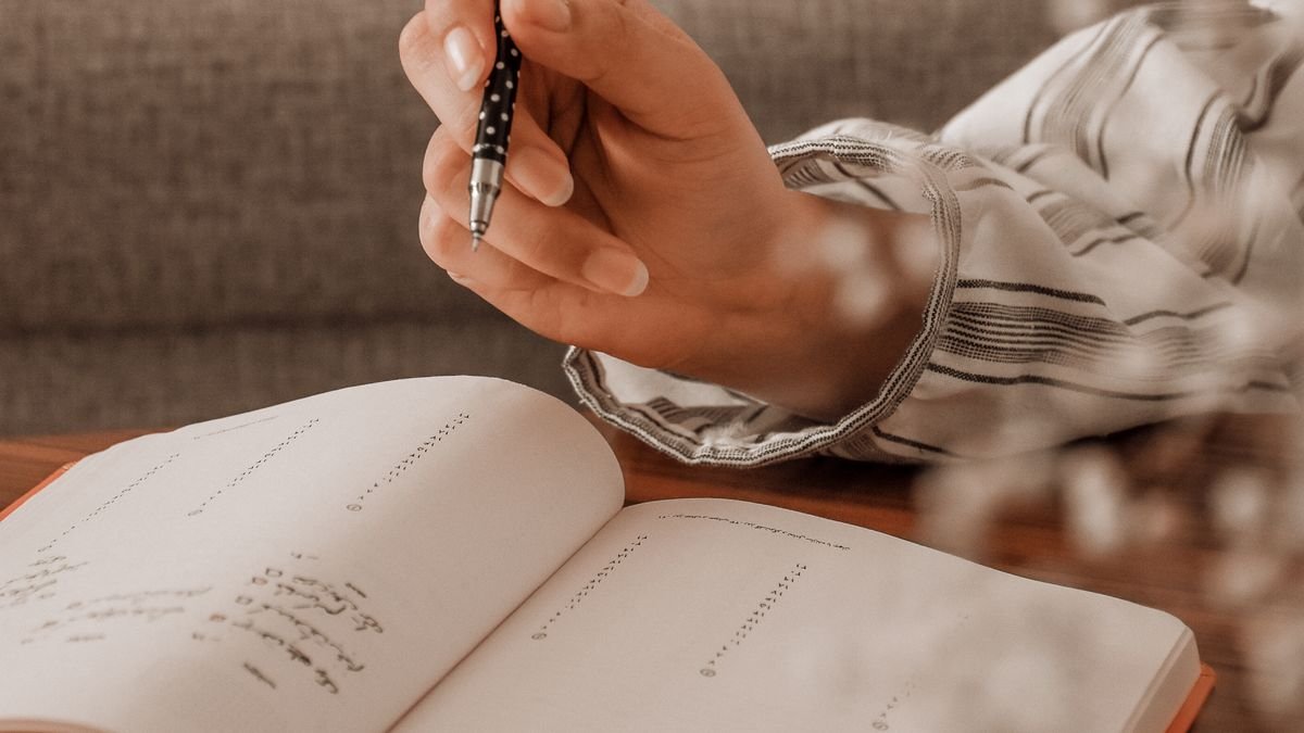 Person writing research notes in a planner while exploring a career