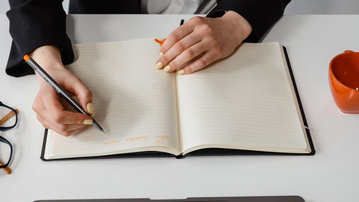 Professional writing notes while comparing training options at a desk