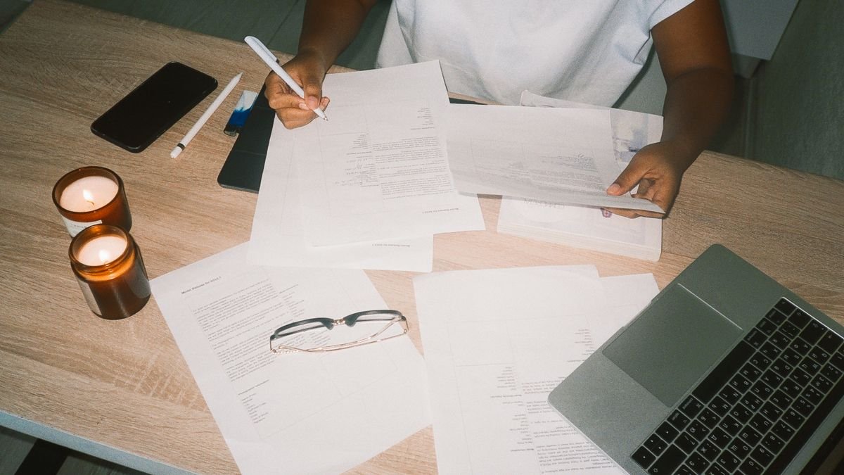 Person working with documents and a laptop while refining an application