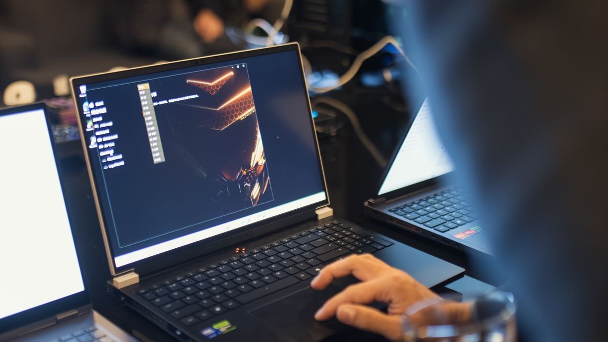 IT professional working on a laptop in a modern office environment