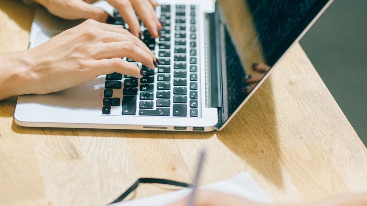 Hands using a laptop and notebook in a digital work setup