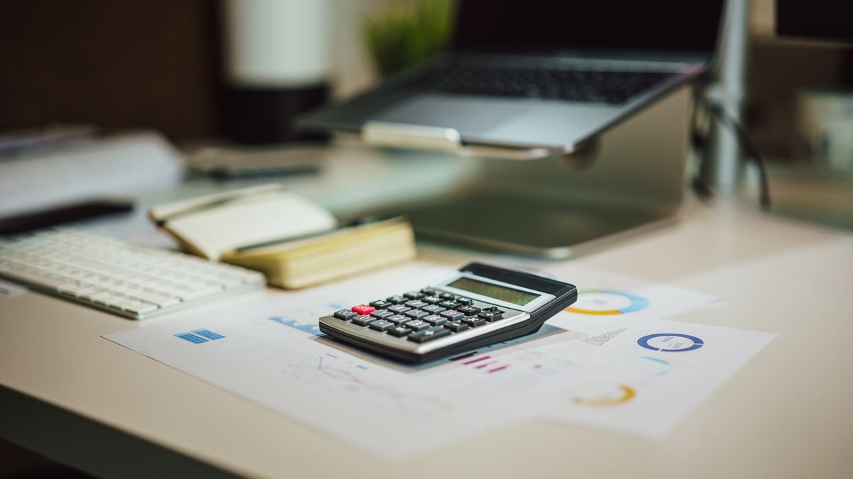 Laptop, calculator, and documents arranged for researching entry-level salaries