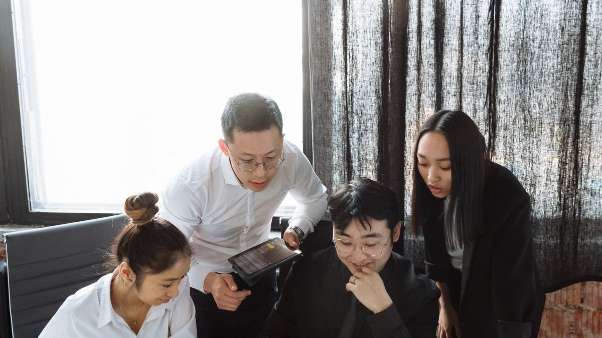 New employee learning with colleagues around a laptop