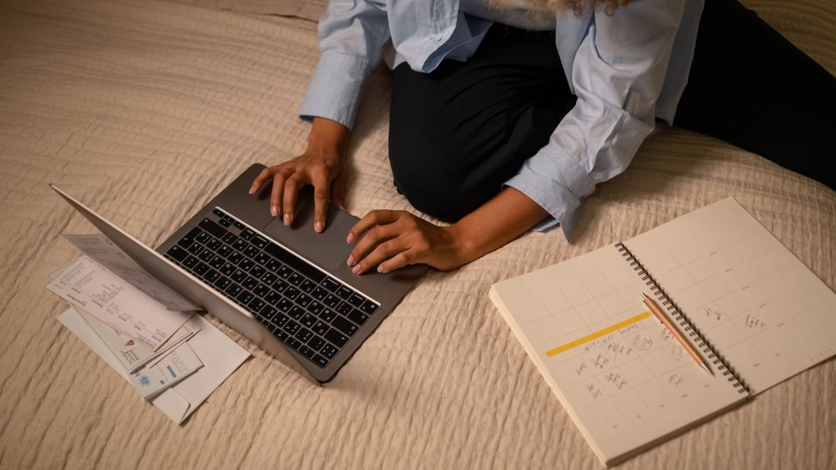 Person using a laptop and notebook to update job application details