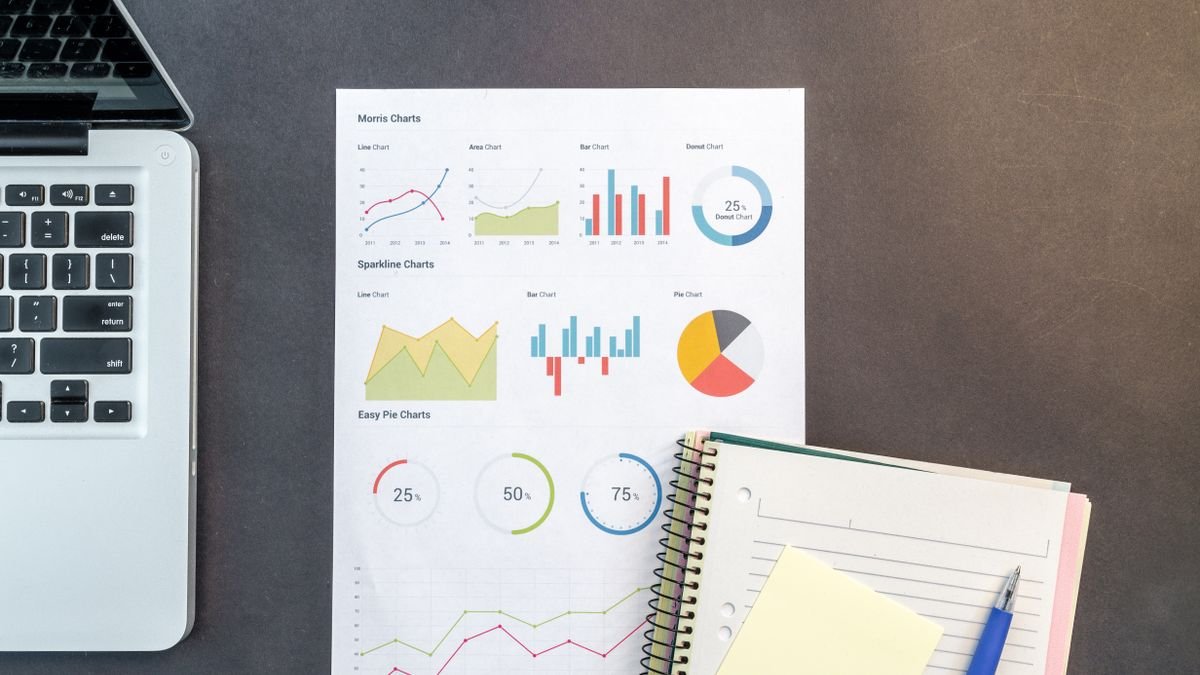 Desk with laptop, notebook, and printed charts used for data analysis practice