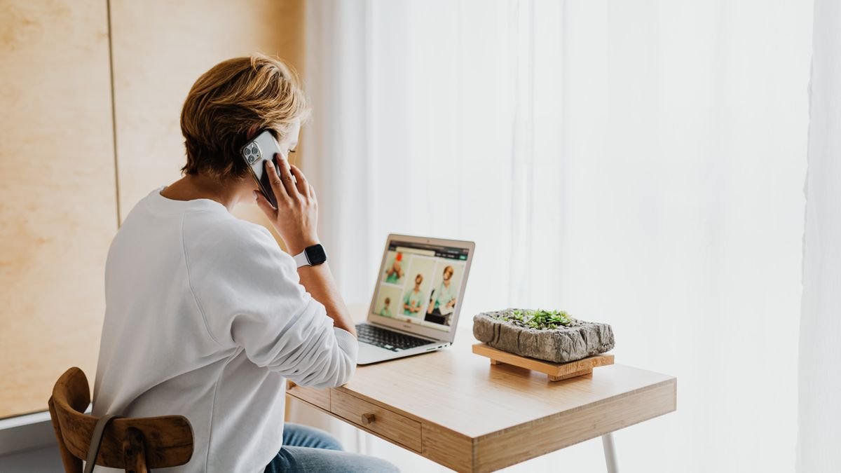 Person speaking on the phone while working on a laptop