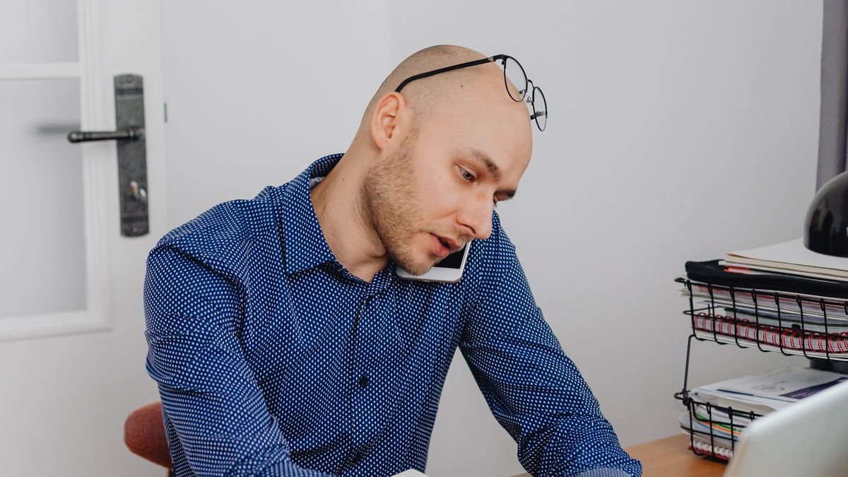 Professional taking a phone call while using a laptop at work