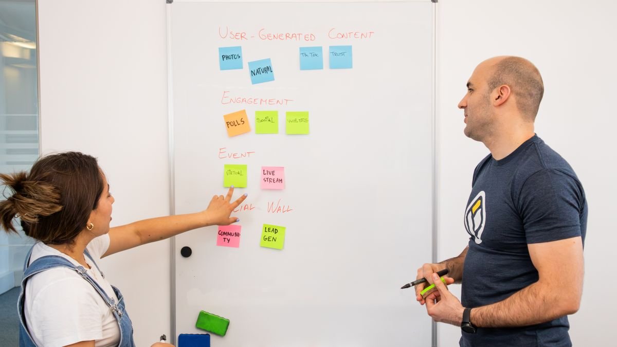 Two professionals brainstorming and planning solutions on a whiteboard