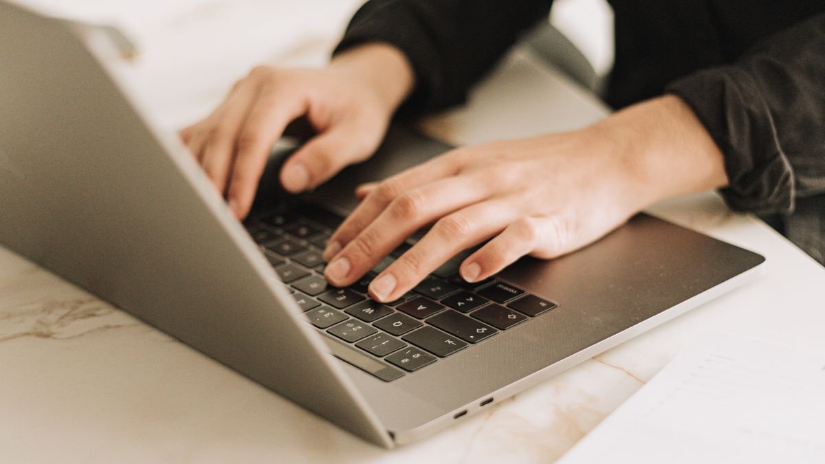 Professional working on a laptop while composing a workplace email
