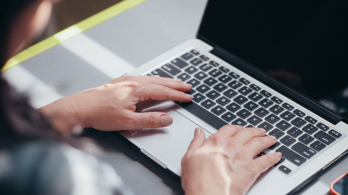 Close-up of hands typing on a laptop for digital workplace communication