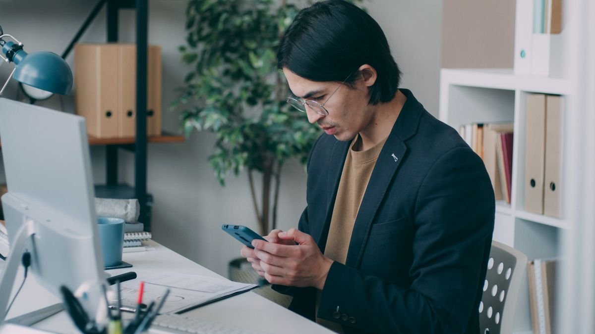 Professional using a smartphone and computer while responding to a recruiter