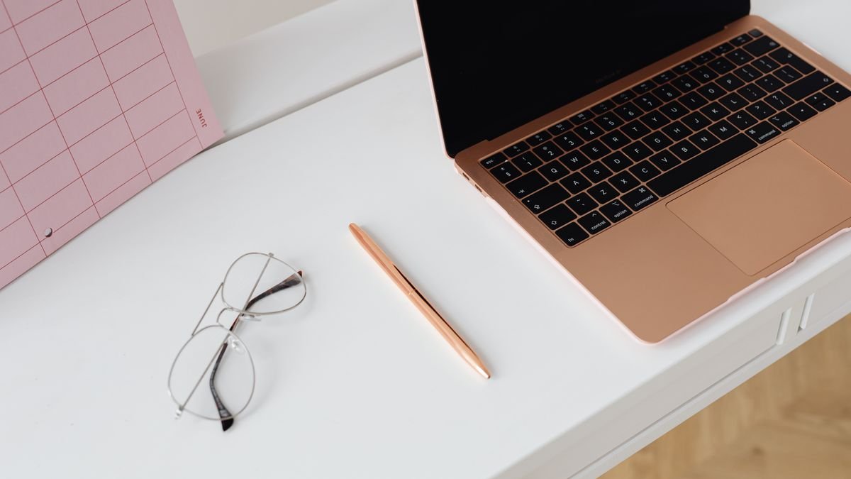 Clean desk with laptop, planner, glasses, and pen for reviewing a resume
