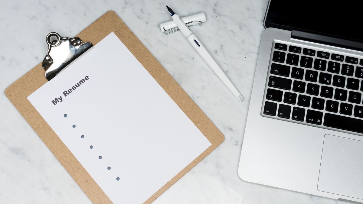 Resume document beside a laptop on a clean desk
