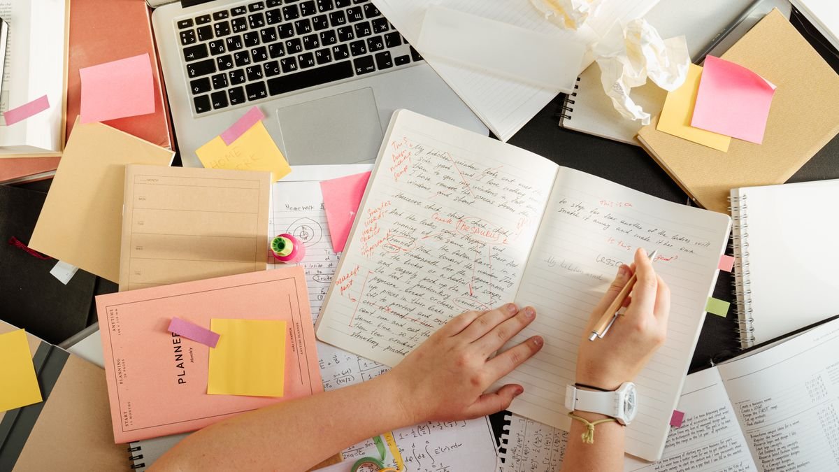 Person organizing written notes beside a laptop
