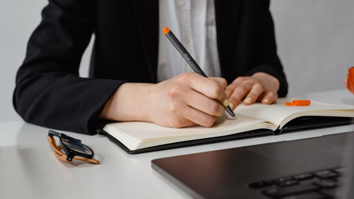 Person making notes in a planner while reviewing skills and experience