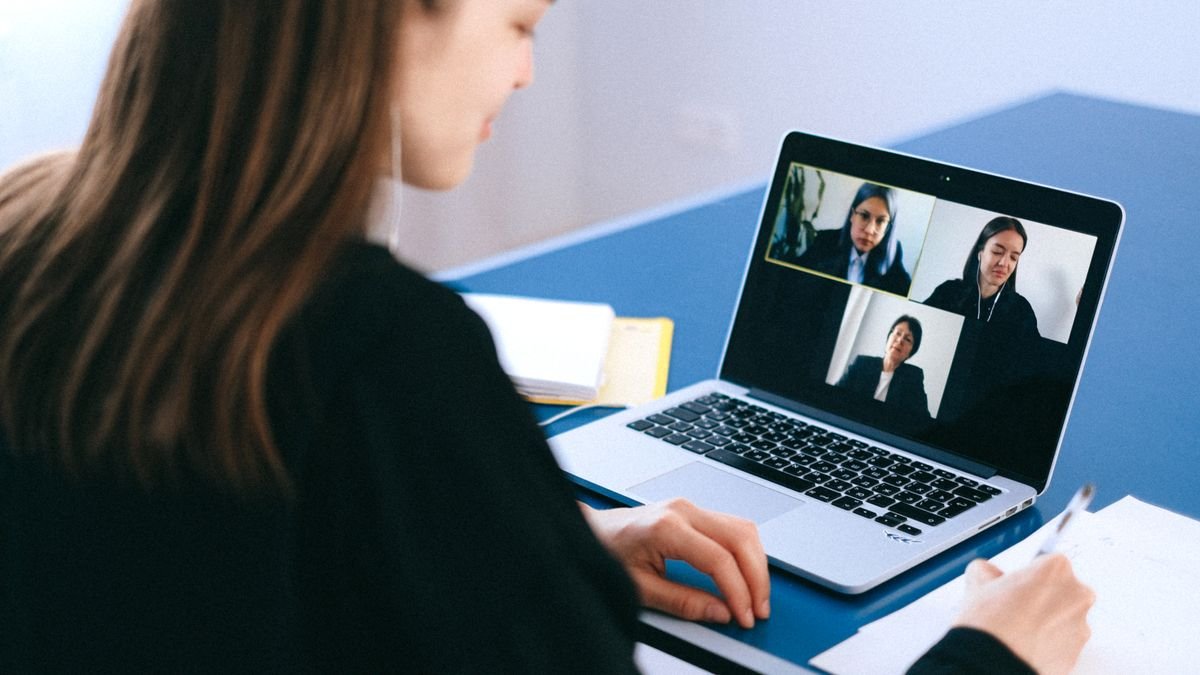 Candidate taking notes during a virtual job interview on a laptop